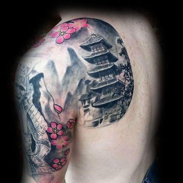 Black and grey shoulder tattoo of a Japanese pagoda with pink cherry blossoms and misty mountains in the background.