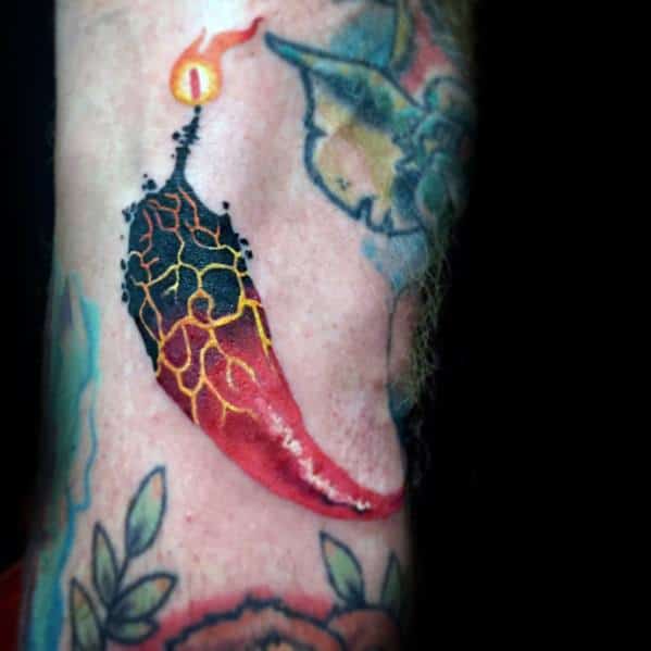 Fiery chili pepper tattoo with a blackened, cracked texture transitioning into red, topped with a burning flame for a bold and intense design.