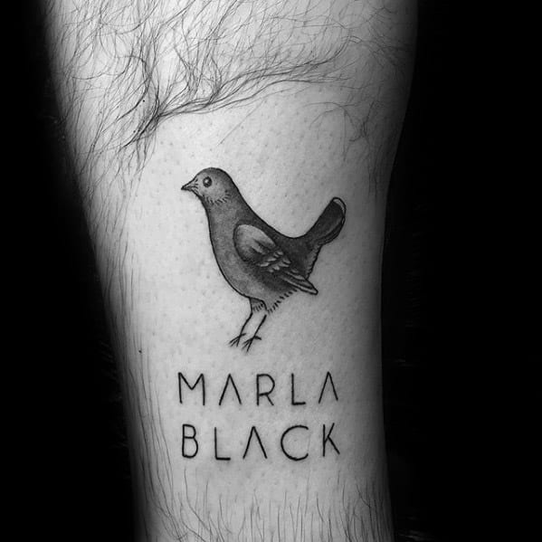 Minimalist black pigeon tattoo above the words “Marla Black,” combining simplicity and personal meaning with clean linework.