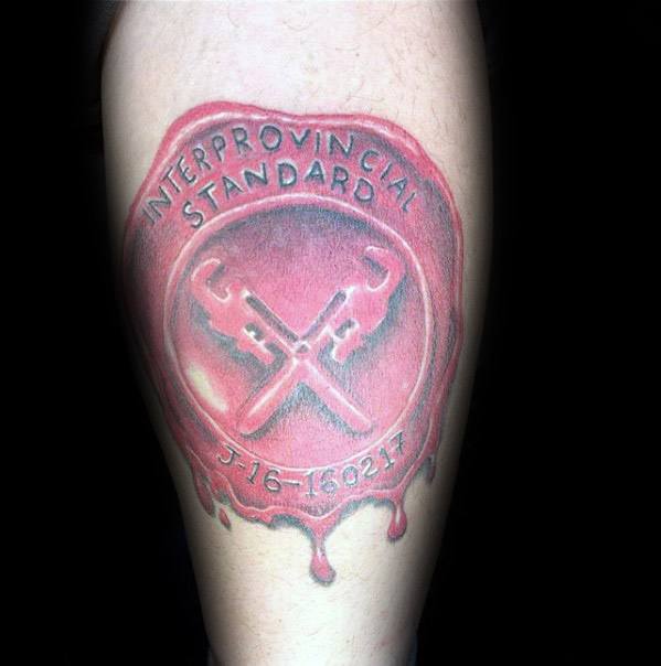 Tattoo of a red wax seal featuring crossed pipe wrenches, the text Interprovincial Standard, and a date at the bottom.