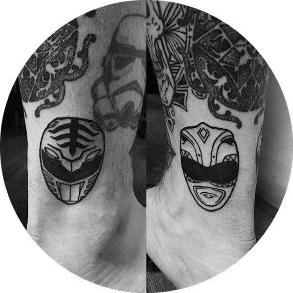 Minimalist ankle tattoos of the White Ranger and Pink Ranger helmets in bold black linework with clean, simple detailing.