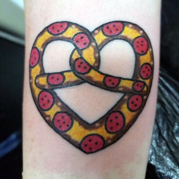 Creative tattoo of a pretzel designed to resemble a pepperoni pizza, featuring melted cheese details and bold black outlines.