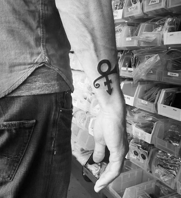 A minimalistic tattoo of Prince's iconic Love Symbol on the wrist, symbolizing his unique identity