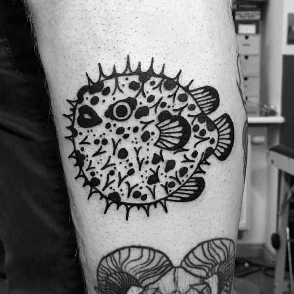 Bold blackwork pufferfish tattoo with intricate patterns and dot details, creating a striking and artistic design on the skin.