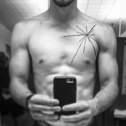Man taking a mirror selfie, revealing a pulsar map tattoo with a starburst design on his upper chest