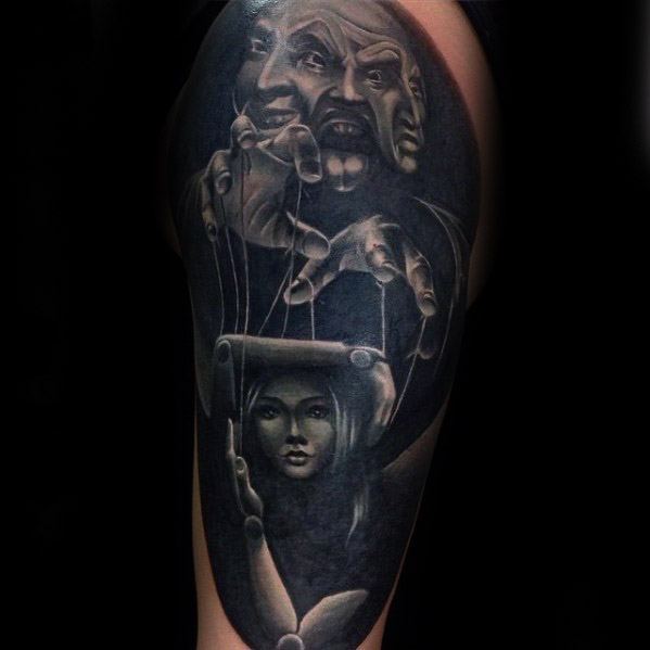Dark surreal puppet tattoo of a female marionette controlled by theatrical masks, symbolizing hidden emotions and manipulation.