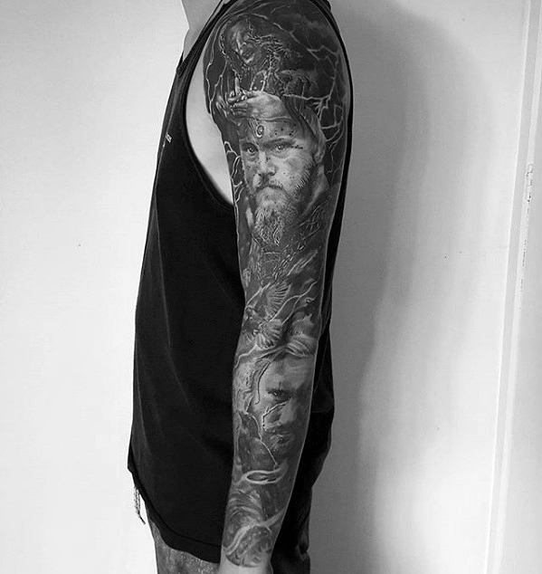 Intricate Viking-inspired sleeve tattoo featuring warrior portraits and mythological elements.