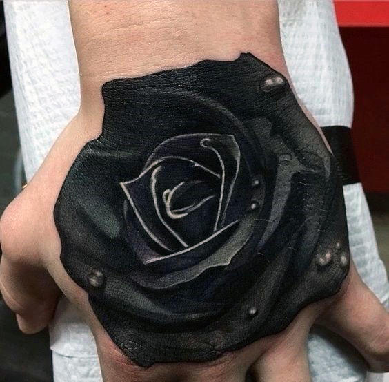 Black rose tattoo on the back of a hand with water droplets