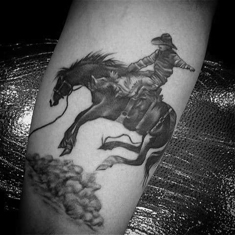 Black and grey tattoo of a cowboy riding a bucking horse, featuring detailed shading, motion effects, and a rugged Western feel.
