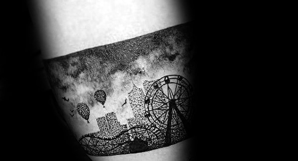 Detailed black ink tattoo of a roller coaster, Ferris wheel, and city skyline with hot air balloons and birds in a cloudy sky.