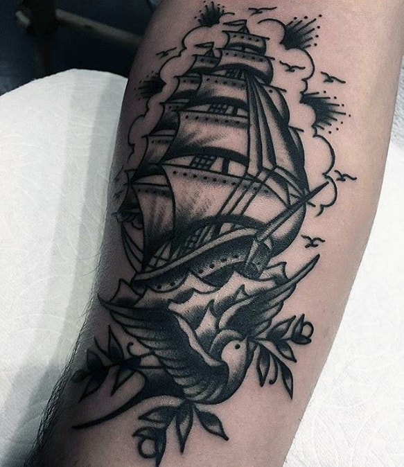 Tattoo of a sailing ship with a bird beneath it, surrounded by clouds and birds