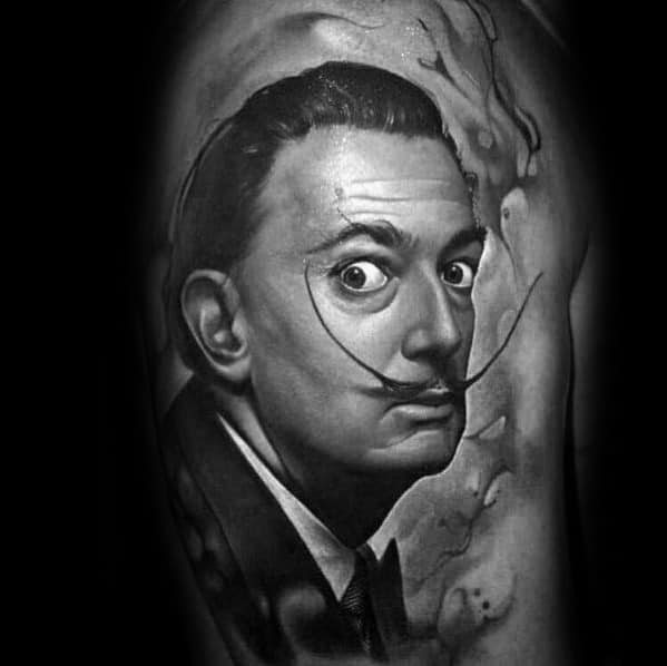 Hyper-realistic black and grey tattoo of Salvador Dali with intense stare, slicked hair, and swirling surreal background elements.