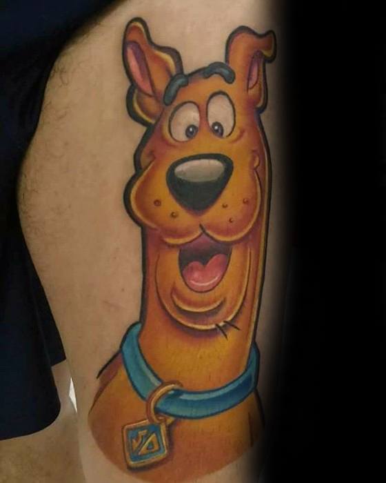 Colorful tattoo of Scooby-Doo smiling with wide eyes, wearing his classic blue collar and tag on an upper leg.