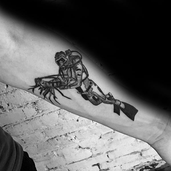 Black and grey scuba diver tattoo on inner arm, featuring diver closely interacting with a lobster underwater.