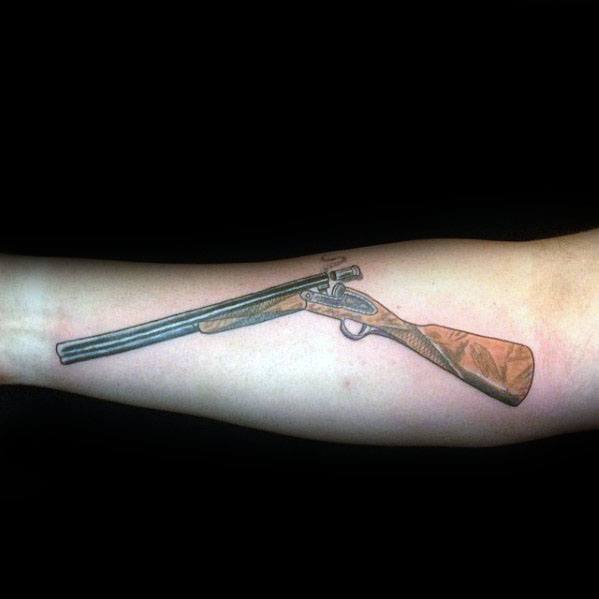 Realistic double-barrel shotgun tattoo on the forearm, featuring fine details and shading for a classic firearm design.