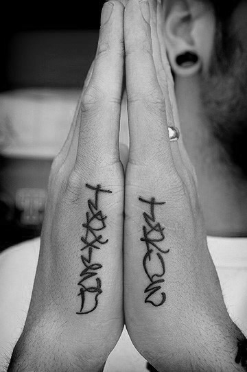 Matching side hand tattoos for men with stylized script reading TATTOO and METAL, placed vertically on the outer edges of each hand.