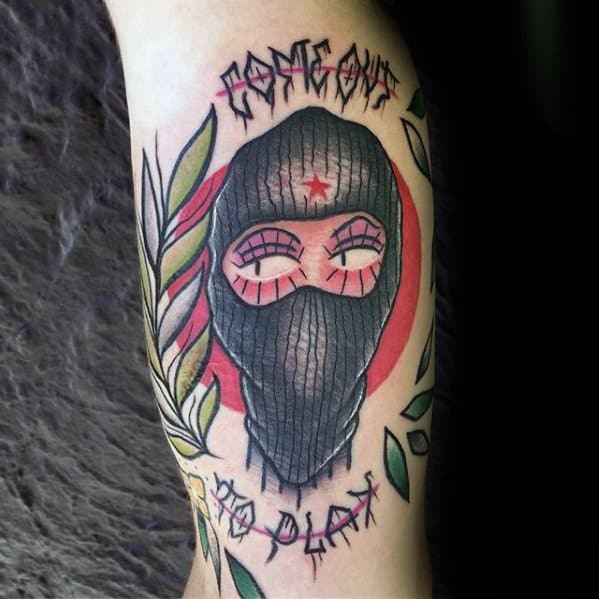 Colorful tattoo of a ski mask with pink eyeshadow, a red star on the forehead, and text reading *Respect* and *No Play*, framed by leaves.