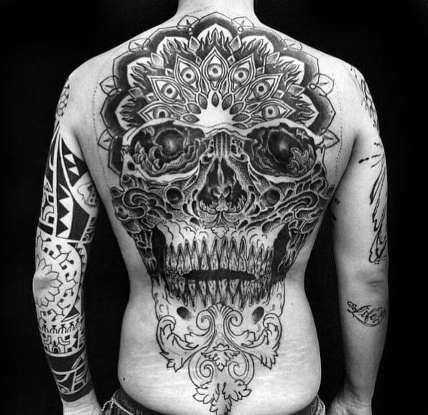 Ornate skull back tattoo merging mandala patterns, tribal details, and fierce textures for a bold and spiritual aesthetic.