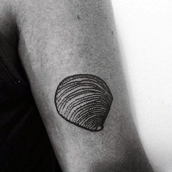 Minimalist clam shell tattoo on the upper arm with fine black line detailing and a clean, simple design.