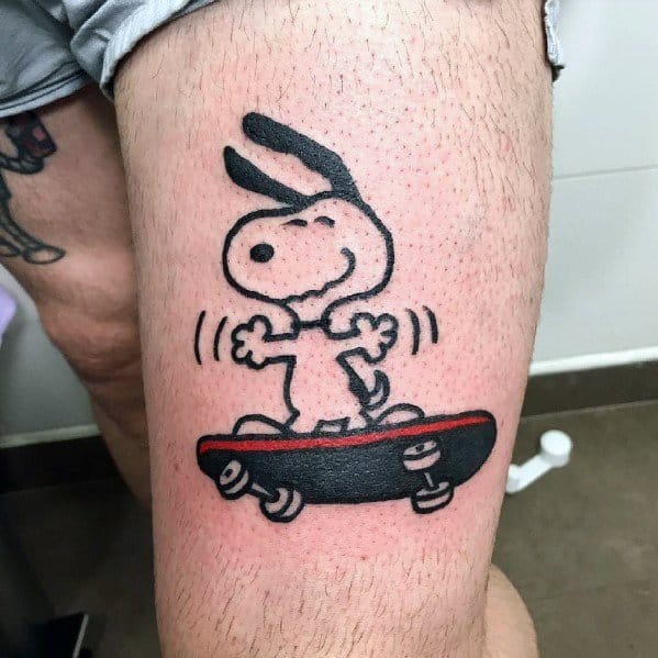 Black and white tattoo of Snoopy balancing on a red and black skateboard with motion lines, placed on a person's thigh.