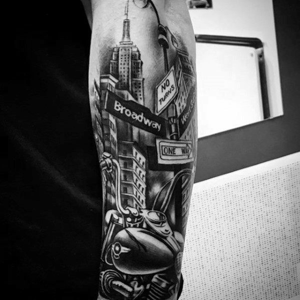 Black and grey tattoo featuring Broadway street signs, the Empire State Building, and a detailed motorcycle in an urban cityscape.