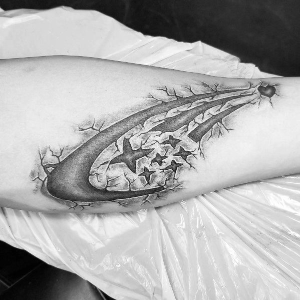 Black and grey Subaru logo tattoo with a 3D ripped skin effect on the forearm, revealing the iconic six-star emblem beneath the surface.