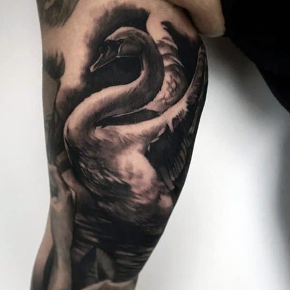 Realistic swan tattoo in black and grey with dramatic shading, capturing the bird’s elegance and motion across the upper arm.