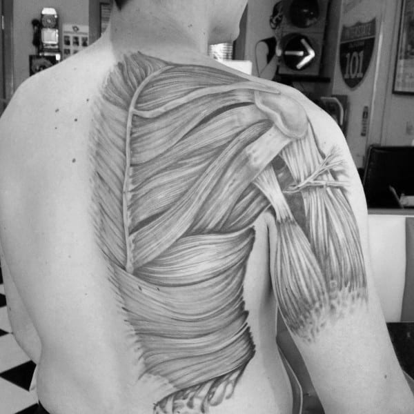 Black and grey tattoo showing detailed back and shoulder muscles, designed to resemble exposed anatomy in a medical illustration style.