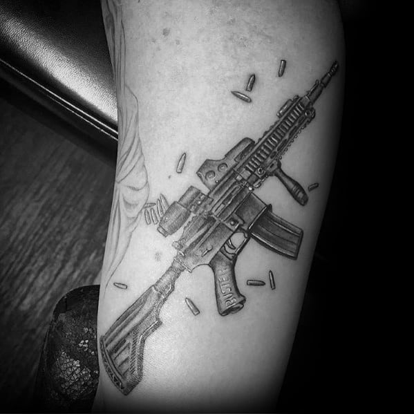 Realistic black and grey AR-15 tattoo with scattered bullet casings, featuring intricate shading and fine details, symbolizing power and readiness.