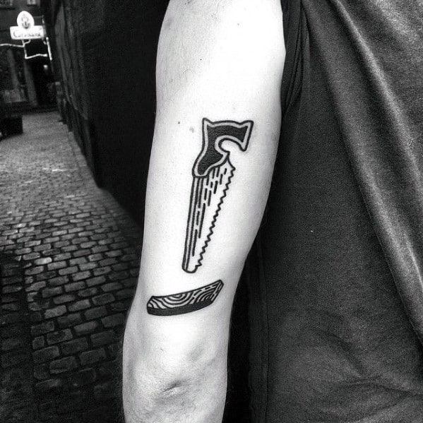 Minimalist tattoo of a hand saw and a wood slice on the upper arm, symbolizing woodworking, craftsmanship, and dedication to the trade.