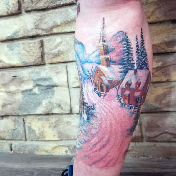 Christmas tattoo of a scenic winter village with snow-covered cottages, a church, pine trees, and a winding path, creating a cozy holiday atmosphere.