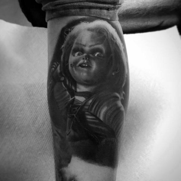 Black and grey Chucky tattoo with dramatic shading, capturing his sinister grin, intense stare, and eerie lighting for a chilling horror design.
