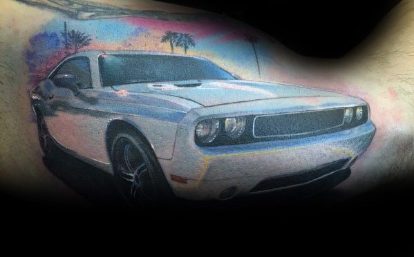 Realistic white Dodge Challenger tattoo with a sunset and palm trees, creating a bold and vibrant muscle car design on the arm.
