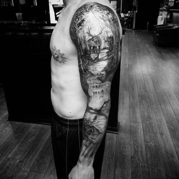 Realistic black and grey full-sleeve tattoo featuring an elk, forest scenery, and detailed shading for a bold and nature-inspired design.