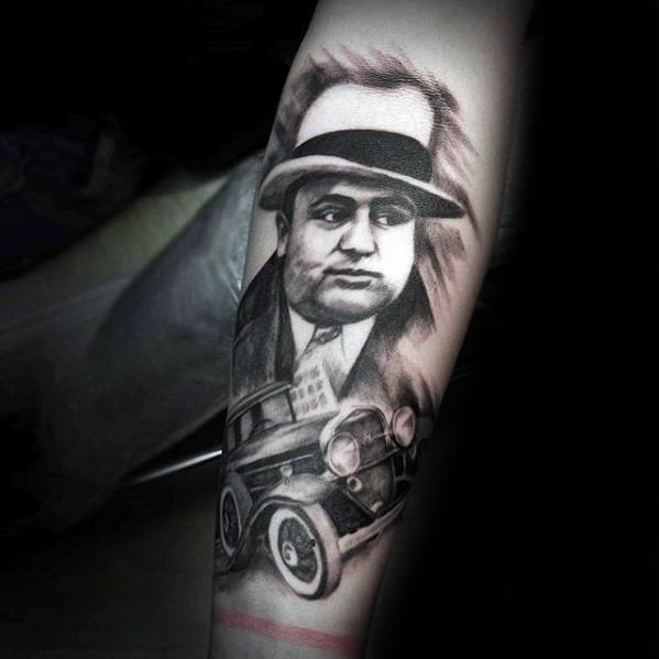 Al Capone tattoo featuring a black-and-white portrait of the gangster, with a vintage car beneath him, capturing the essence of his era.