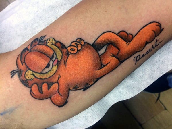Garfield tattoo in a relaxed pose with a smug grin, stretching across the arm—bold colors and playful design for a chill vibe.