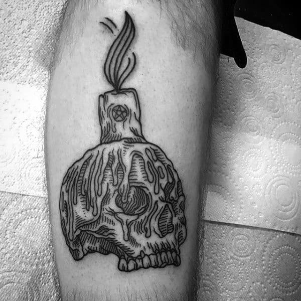 Black and grey tattoo featuring a melting skull candle with a pentagram on the wax, blending gothic and occult elements in bold linework.