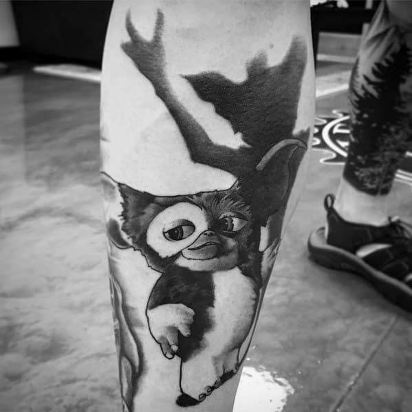 Black and gray Gizmo tattoo with a shadowy Gremlin figure in the background, creating a striking contrast between innocence and menace.
