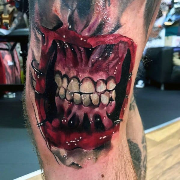 Brutal *Hellraiser*-inspired tattoo of a ripped-open mouth with exposed teeth, vivid red tones, and intense shading for a gruesome effect.