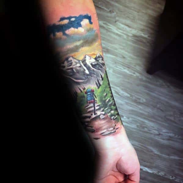 Colorful hiking tattoo featuring a backpacker on a mountain trail with trees, clouds, and a sunset sky, symbolizing adventure and exploration.