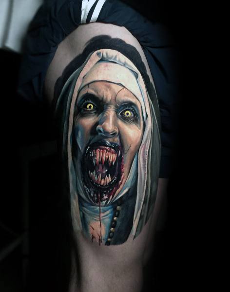 Realistic horror tattoo of Valak from *The Nun*, featuring glowing yellow eyes, sharp fangs, and eerie shading for a terrifying and haunting effect.