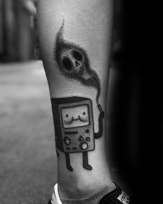 Black and grey Adventure Time tattoo of BMO holding a smoking device with a ghostly skull emerging from the smoke, placed on the calf.
