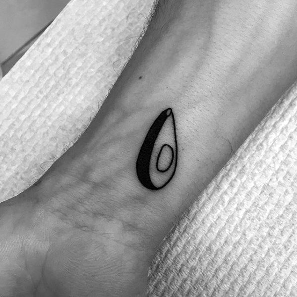 Tiny minimalist avocado tattoo on the ankle with bold black outlines and clean geometric shapes for a sleek modern look.