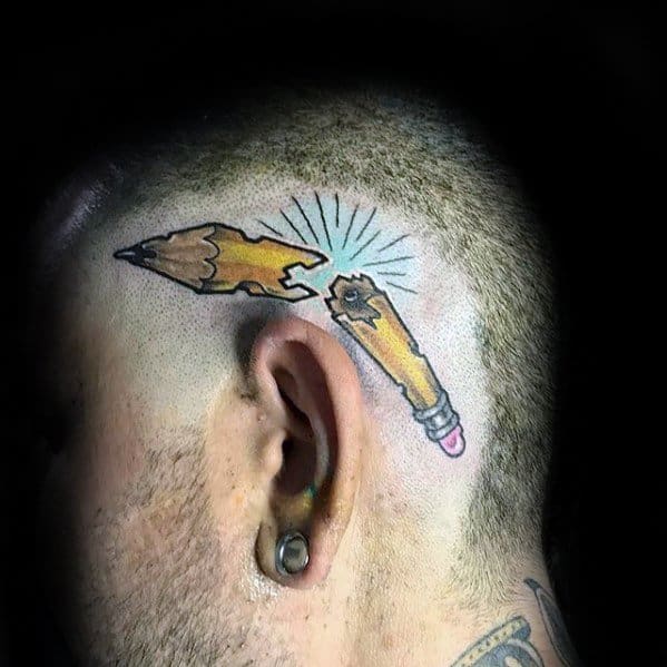Tattoo of a pencil broken in half etched on a person's shaved head just behind the ear, symbolizing creativity and resilience