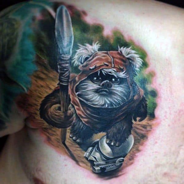 Realistic Ewok tattoo with a large spear, walking through a forest trail while stepping on a fallen Stormtrooper helmet.