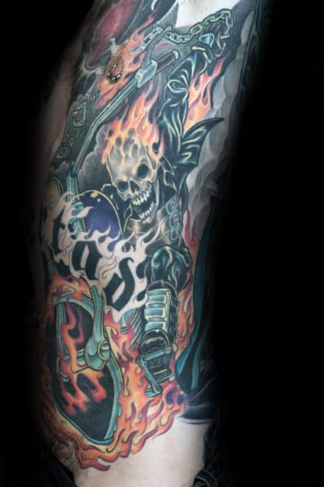 Colorful Ghost Rider side torso tattoo with a flaming skull, blazing motorcycle, bold chain, and dynamic flames surrounding the figure.