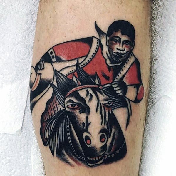 Bold traditional-style tattoo of a jockey riding a horse, featuring strong black outlines, red accents, and expressive facial features