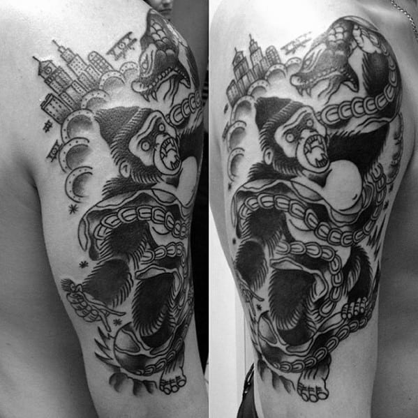 Blackwork King Kong tattoo on upper arm in traditional style, featuring broken chains, planes, city skyline, and stars in the background.