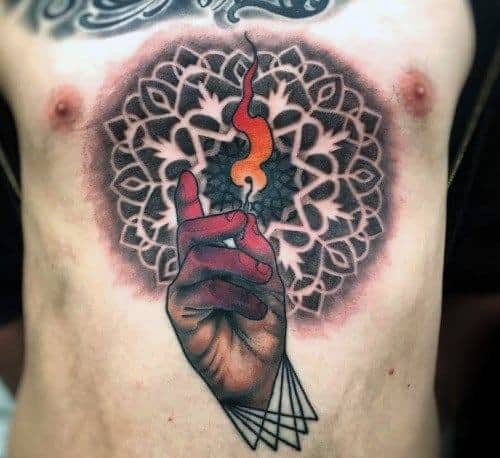 Intricate chest tattoo of a hand holding a burning match against a mandala-style background, symbolizing inner fire, enlightenment, and spiritual awakening.
