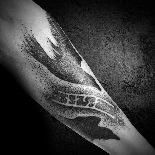 Abstract dotwork tattoo of Odin’s ravens in flight with runes across the forearm, blending shadows and negative space.